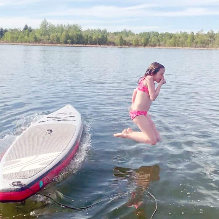 Girl jumping off a paddleboard into Spring Lake, Alberta