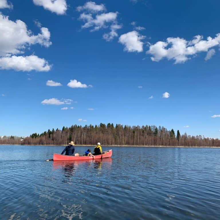 Three people canoeing towards Osprey Island on Spring Lake in Alberta